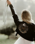 Celestial-inspired black leather jacket designed for brides, adorned with moon and stars embroidery for a trendy and personalized wedding cover-up