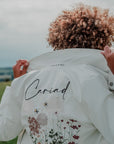 Boho-Chic Wildflowers Bridal Jacket: Complete your bridal look with this ecru cover-up featuring intricate wildflower embroidery, adding a whimsical and romantic touch to your ensemble