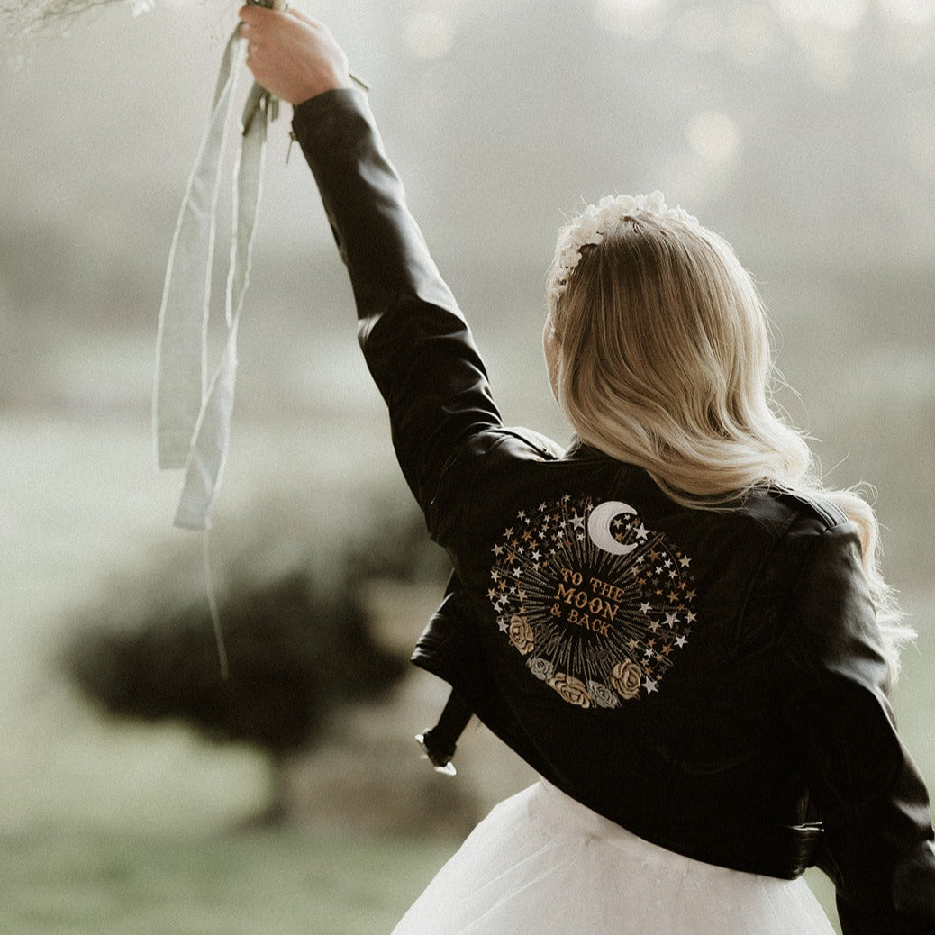 Celestial-inspired black leather jacket designed for brides, adorned with moon and stars embroidery for a trendy and personalized wedding cover-up