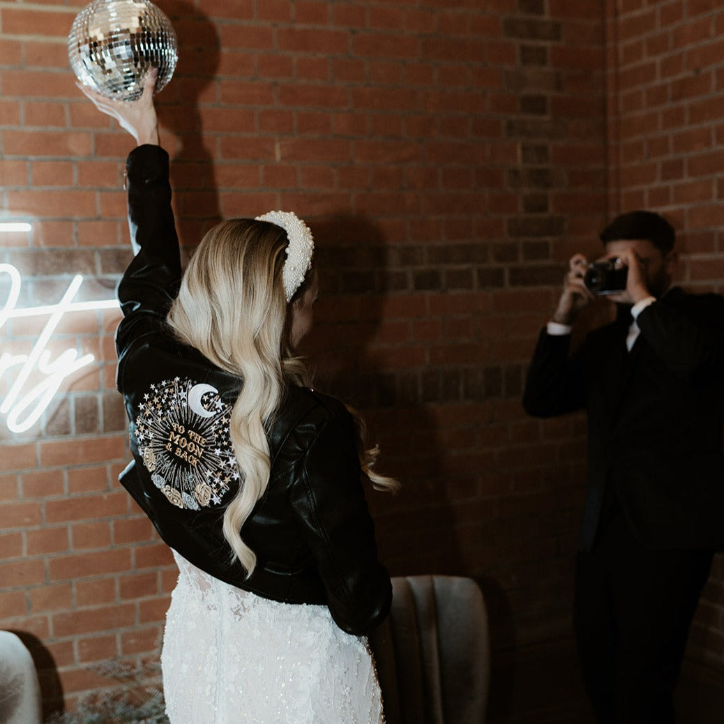 Custom black leather bride jacket with celestial motifs, including moon and stars embroidery, creating a one-of-a-kind wedding cover-up for the modern bride