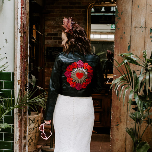 Chic black cropped leather jacket for brides, a custom bridal cover-up featuring a red and pink color scheme – a stylish choice for a Valentine's-themed wedding ensemble