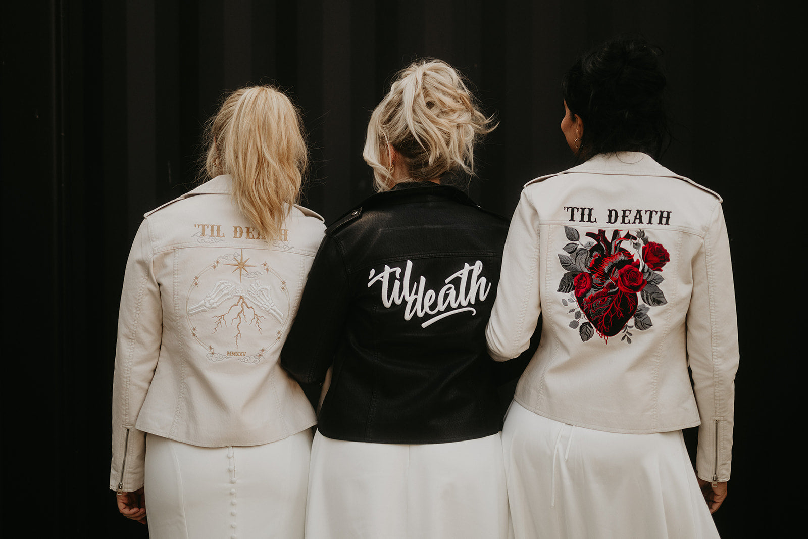 Three women wearing personalized jackets with unique designs on a black background